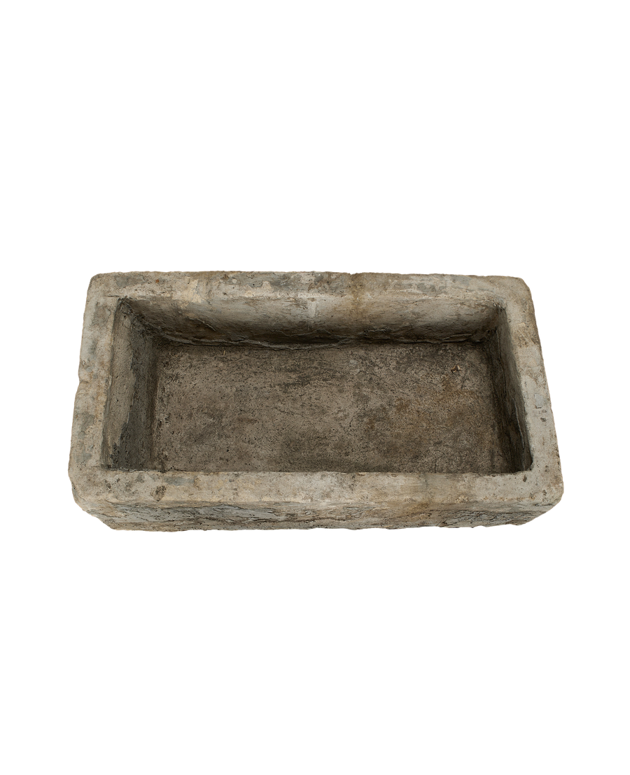 Top-down view of a vintage rectangular limestone trough with rough, aged texture.