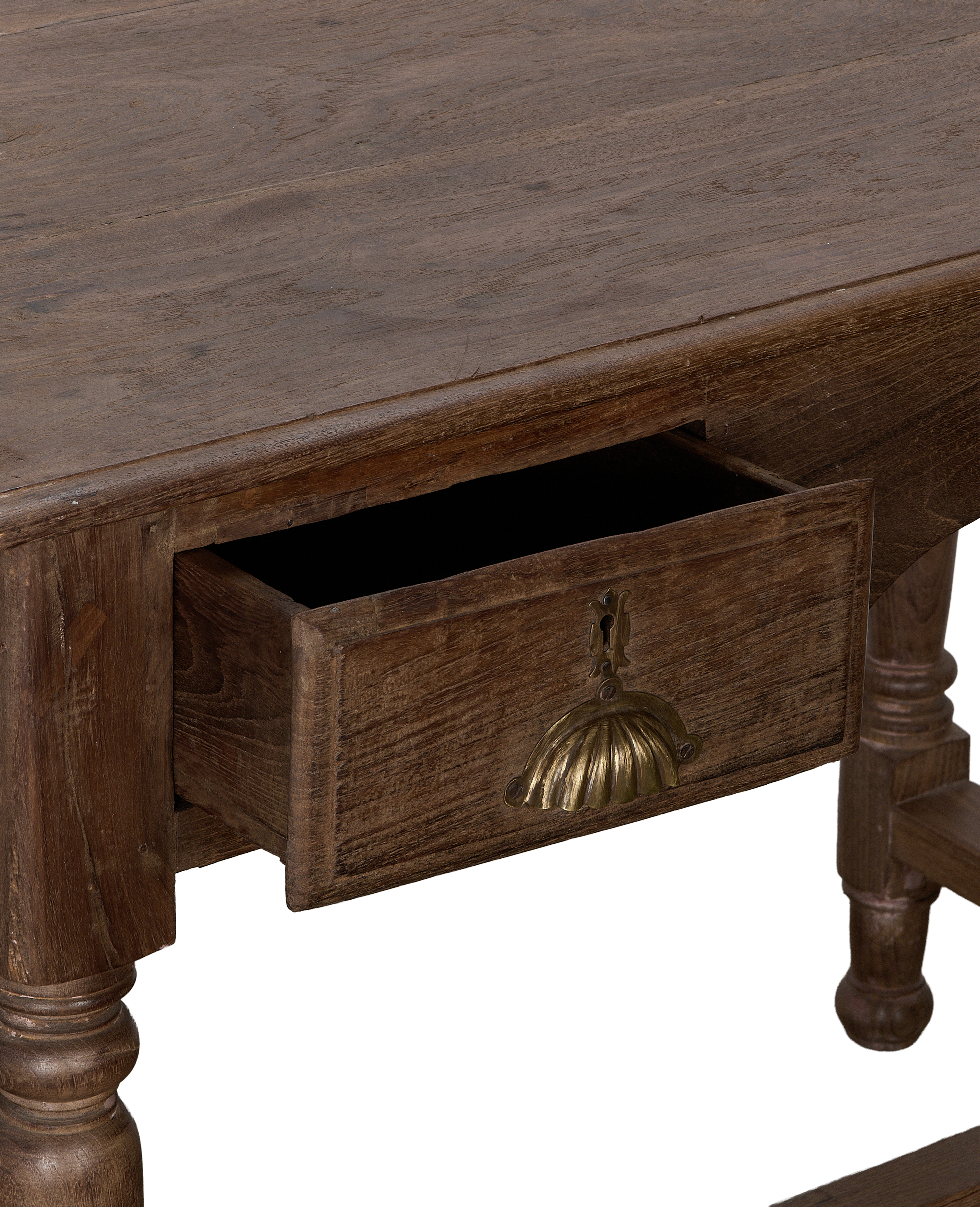 Partially open drawer of a vintage oak wood desk with ornate brass pull.