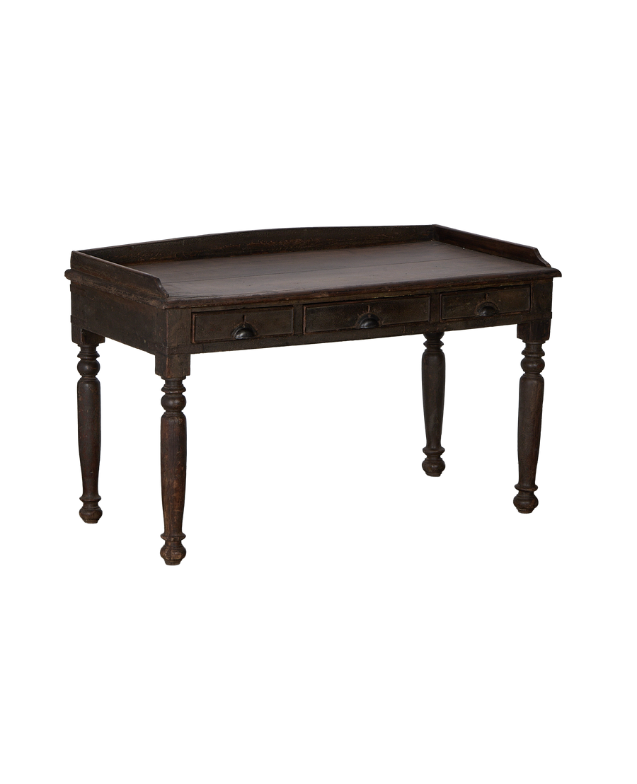Dark vintage oak wood desk from India, showing three drawer fronts, turned legs.
