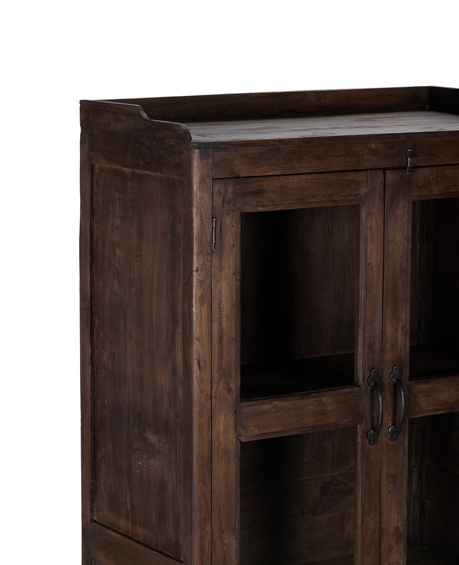 Angled view of vintage Indian oak wood cabinet, showcasing distressed finish and glass doors.