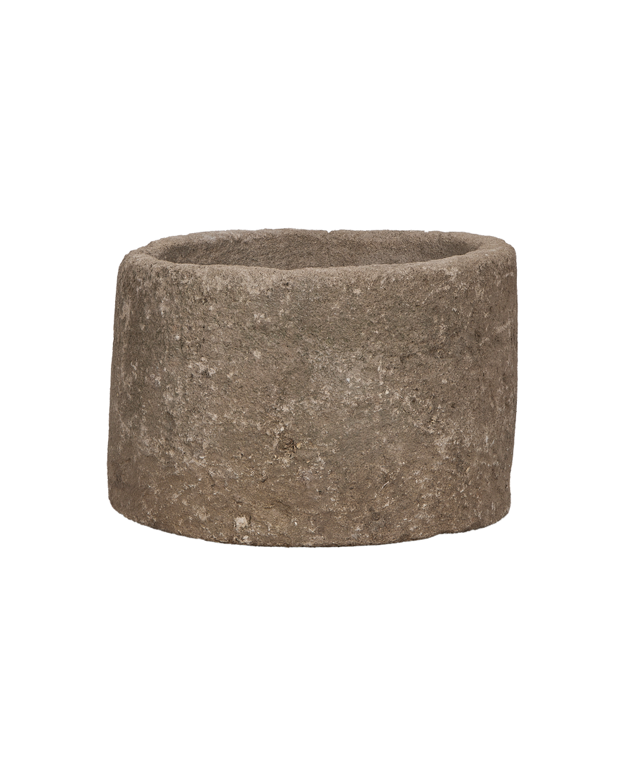 Vintage Indonesian round limestone trough, close-up texture detail from a low angle.