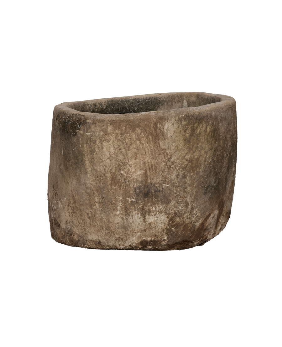 Vintage Indonesian limestone trough, showing its rough, weathered texture and rounded shape from a lower angle.