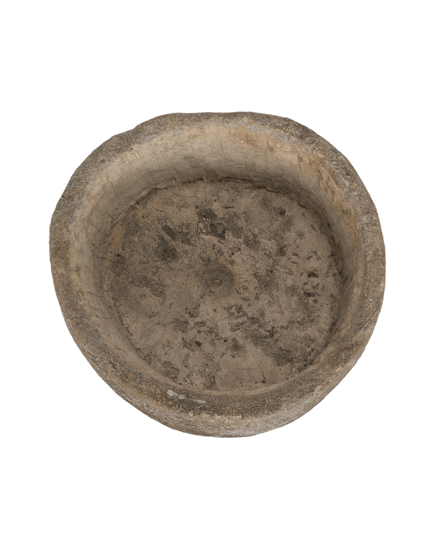 Top-down view of a vintage round limestone trough with textured interior.