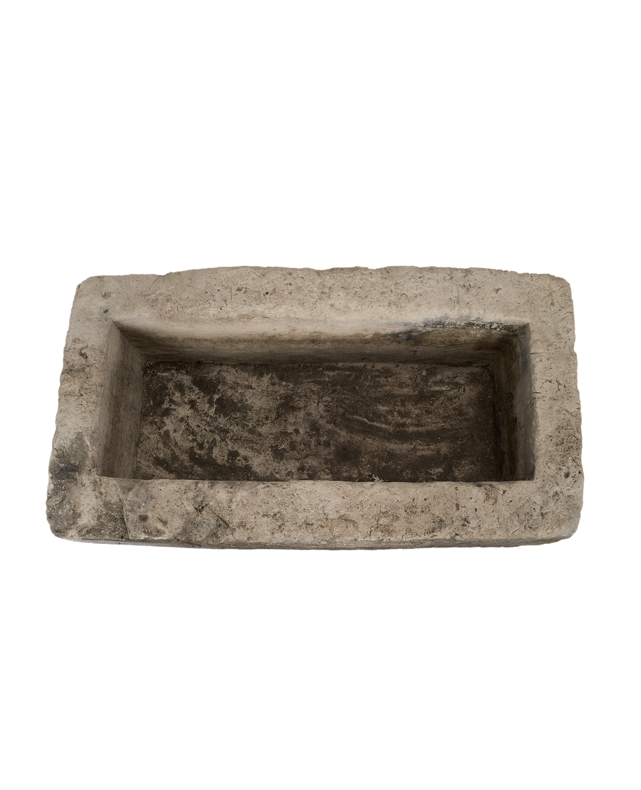 Vintage rectangular limestone trough, showing the rustic, rough interior with dark stains.