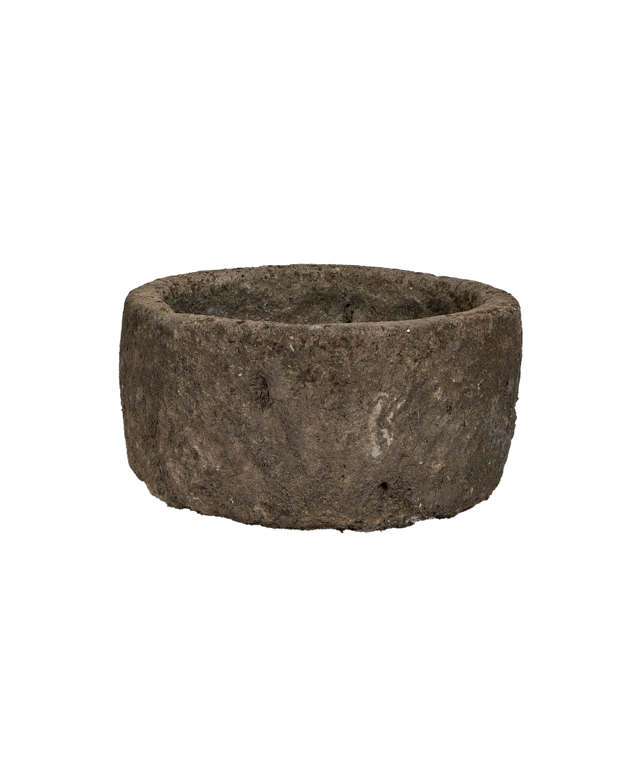 Vintage Indonesian limestone trough, displaying round shape, rough exterior texture, and weathered condition.
