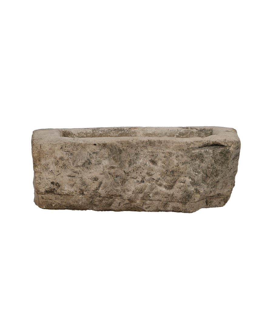Vintage rectangular limestone trough, showing its aged, weathered surface texture from a side view.