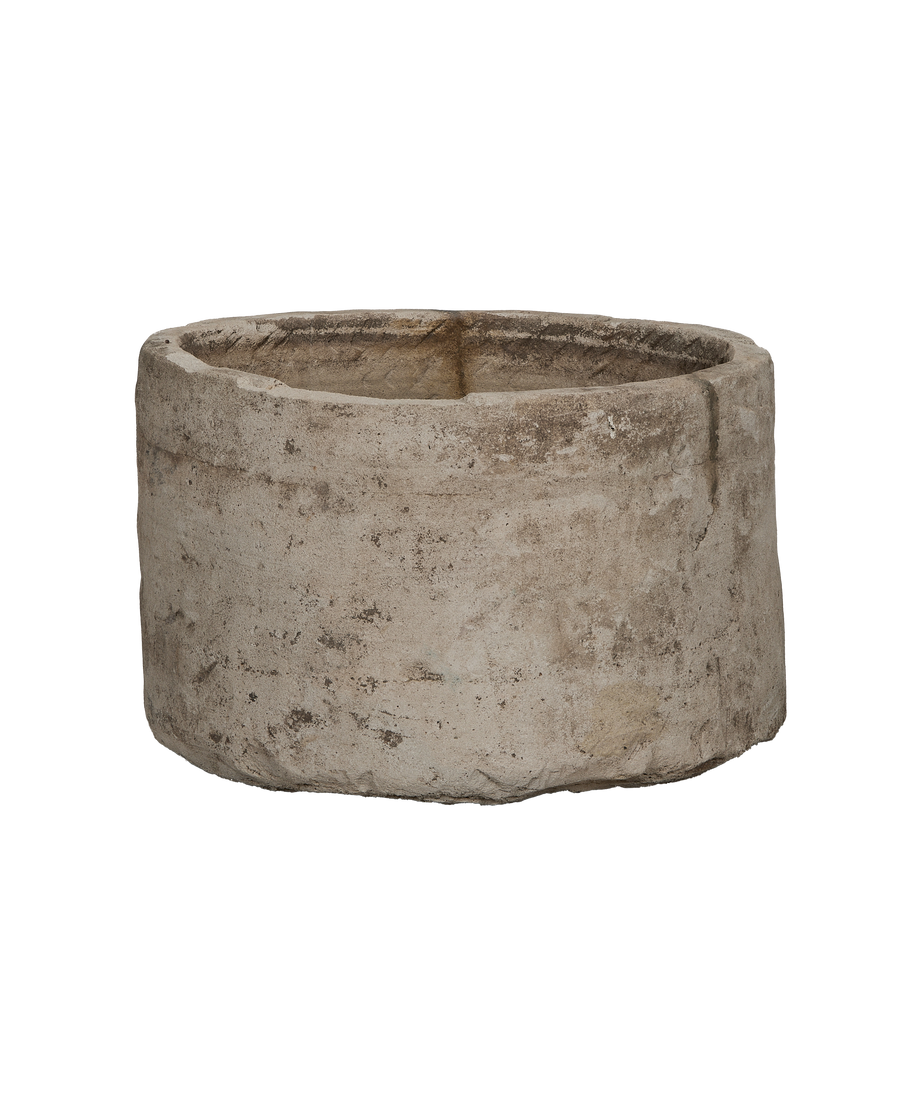 Vintage round limestone trough, side view revealing rustic texture and natural imperfections.