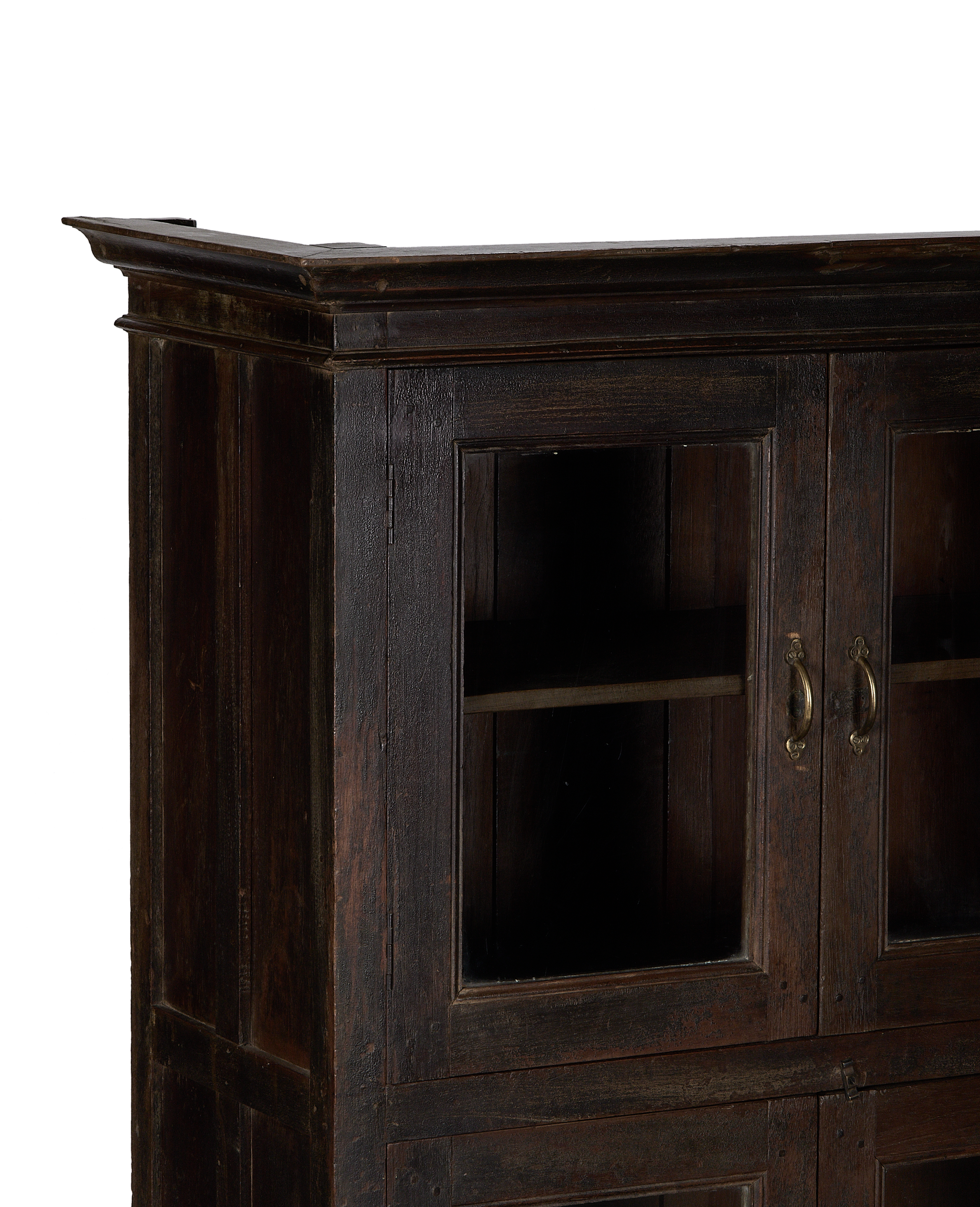 Close-up of vintage Indian oak wood cabinet with glass doors and brass handles.