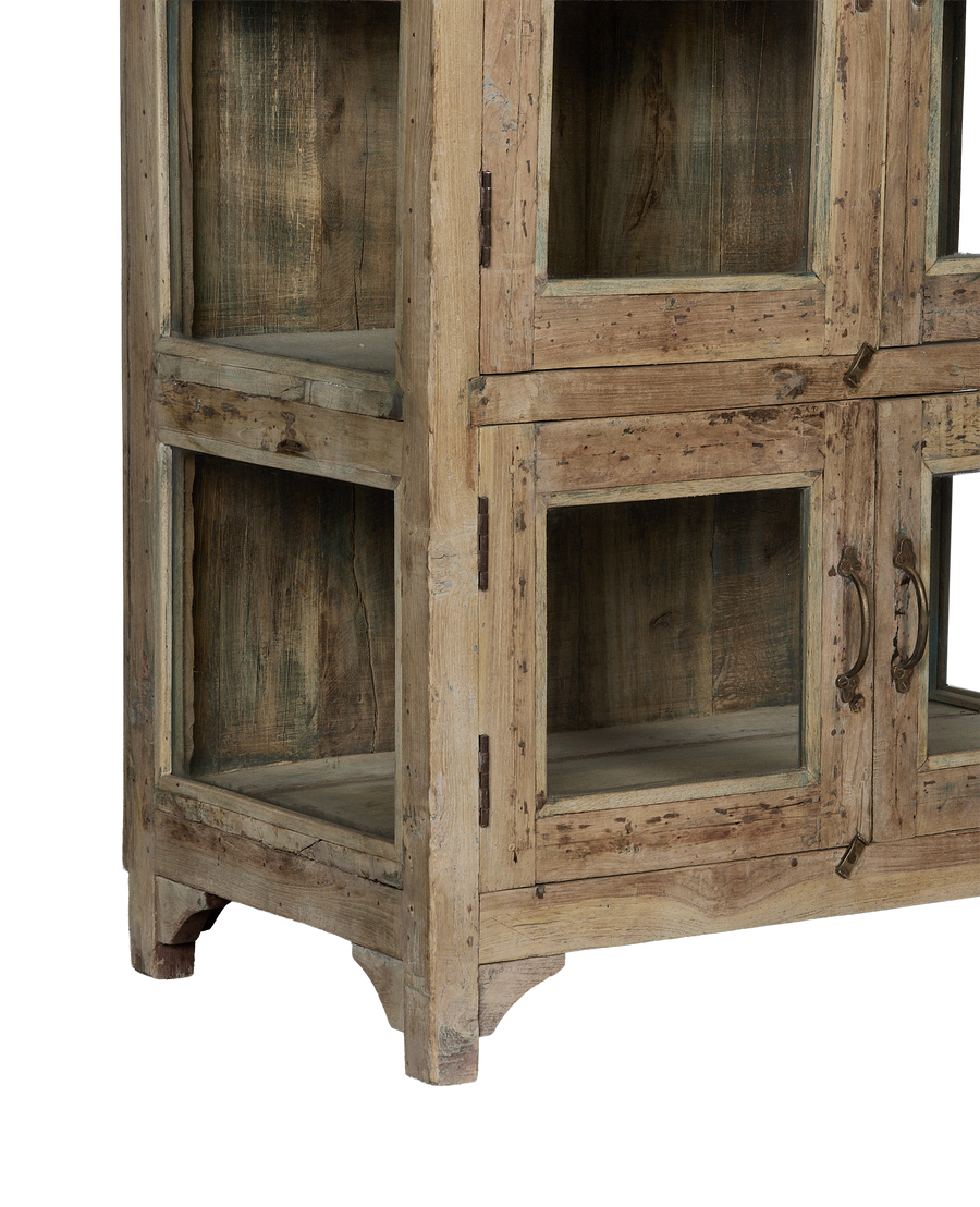 Vintage bleached oak cabinet from India, showing rustic panels, glass doors, and distressed wooden supports.