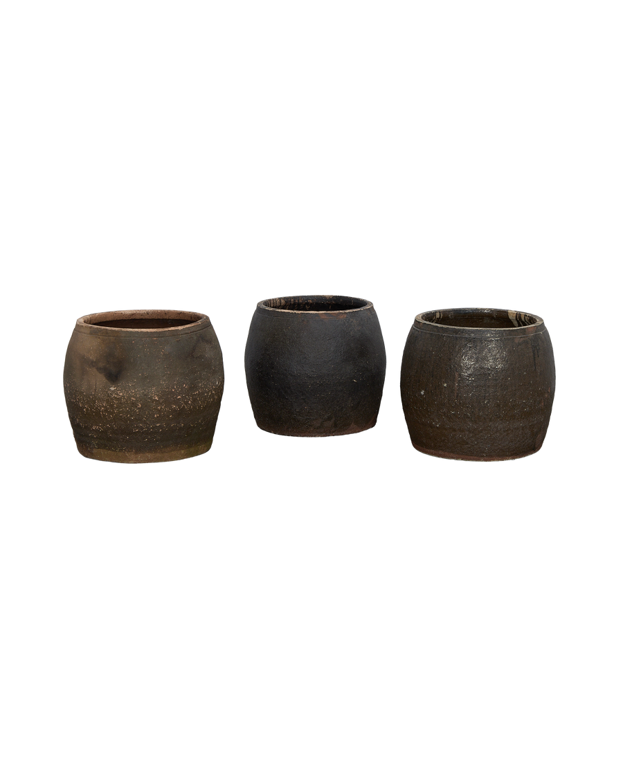 Three distressed vintage Chinese terracotta planters in various earth tones on black background.