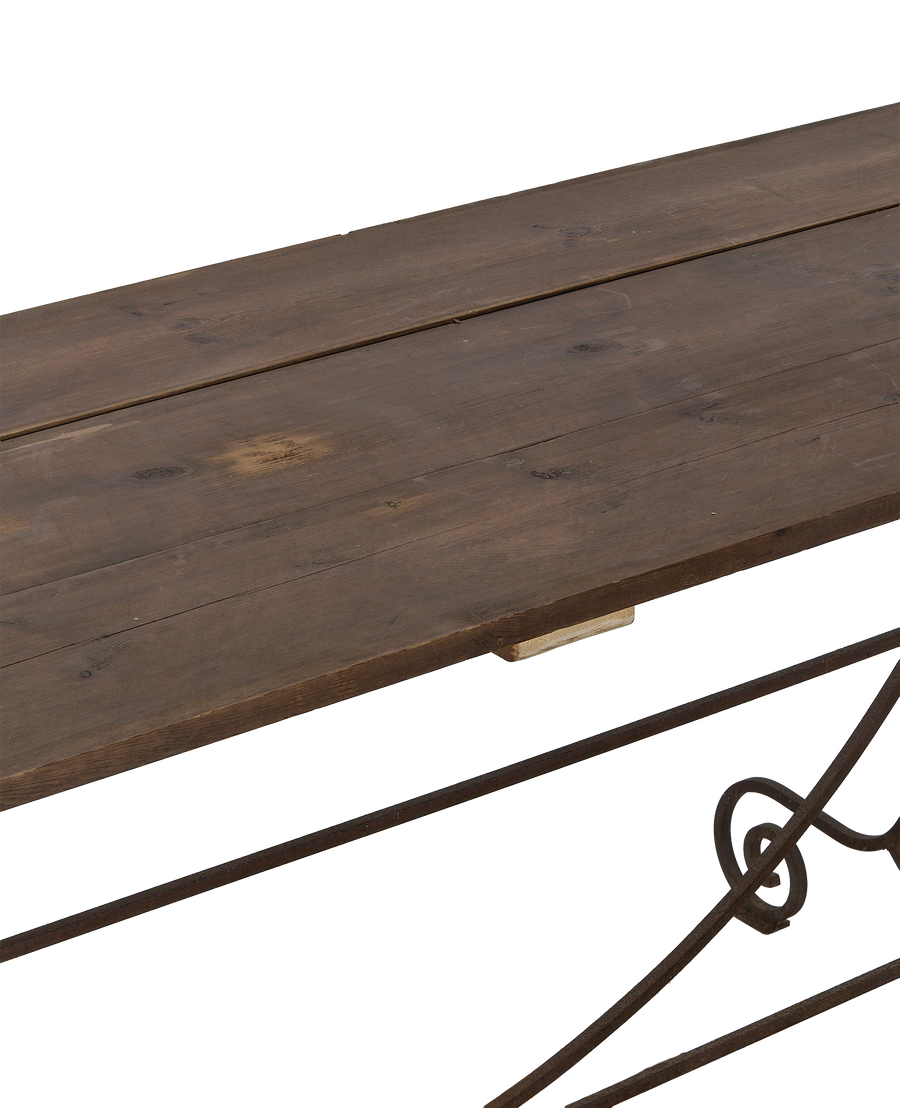 Close-up angle of weathered vintage oak tabletop planks and ornate wrought iron frame.
