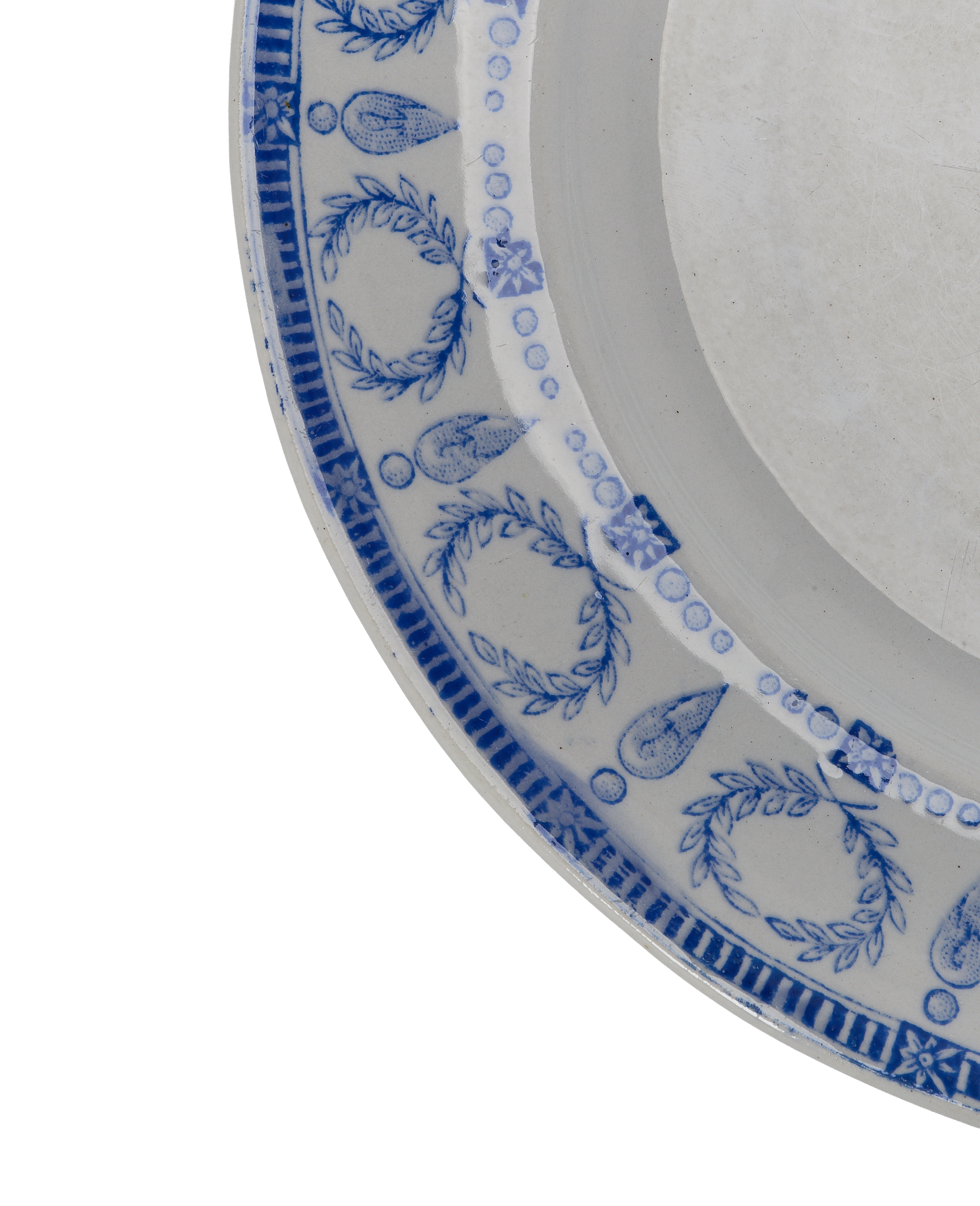 Close-up of vintage French blue motif plate rim, showcasing detailed floral and laurel wreath patterns.