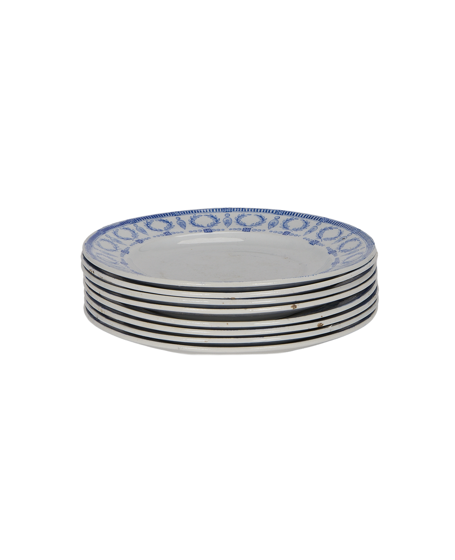 Stacked vintage French plates, blue motif, showing aged rims and signs of wear.
