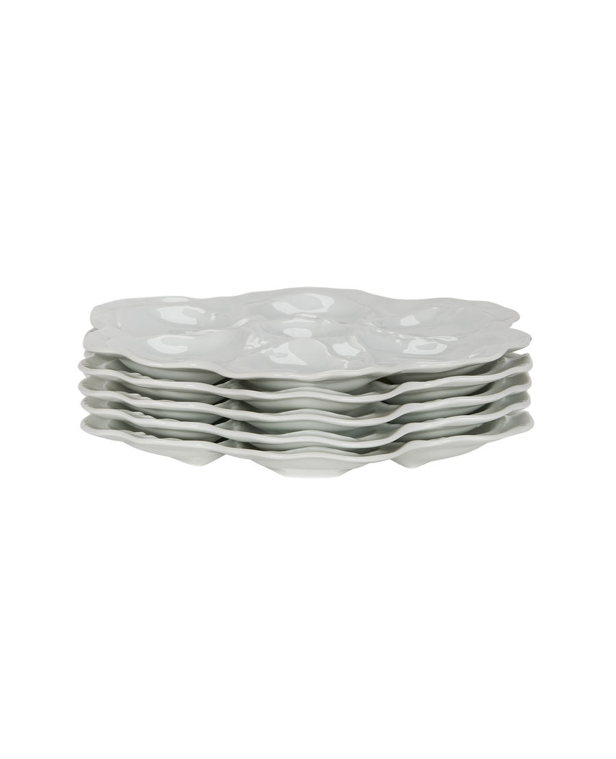 Stacked white Limoges oyster plates, six vintage French porcelain dishes, showing curved edges.