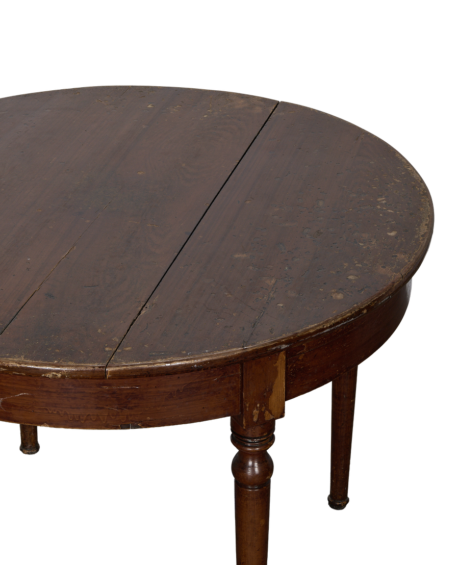 Close-up of vintage French oak round dining table with distressed tabletop and turned legs.