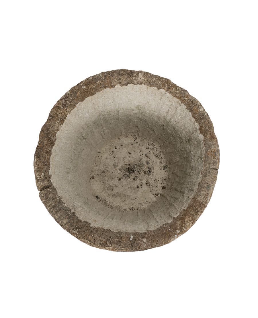 Vintage round limestone trough, top-down view showing weathered interior texture and rough rim.