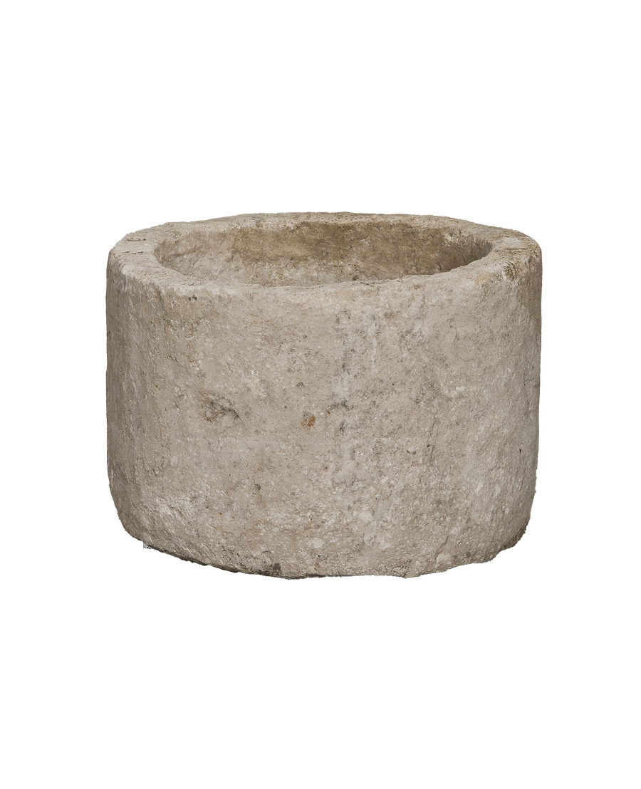 Vintage round limestone trough, side view revealing rustic texture and natural imperfections.