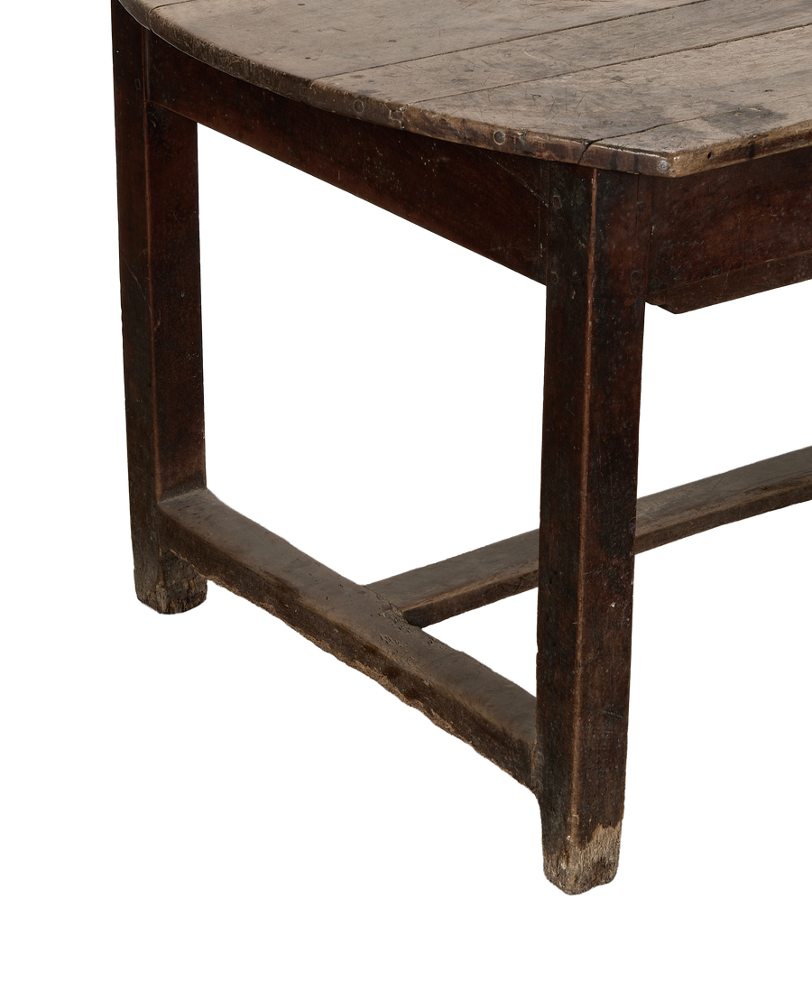 Vintage French oak dining table, close-up of distressed leg, curved edge, and wooden crossbar.