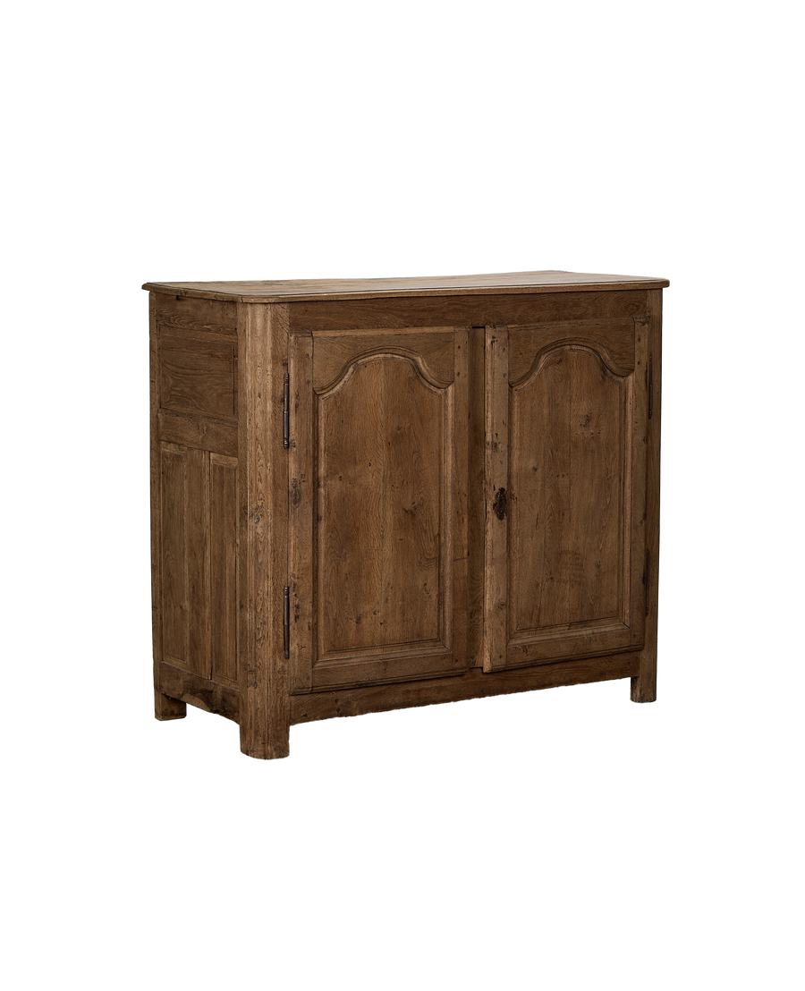 Vintage French oak sideboard angled view, showcasing rustic wood grain and ornate door carvings.