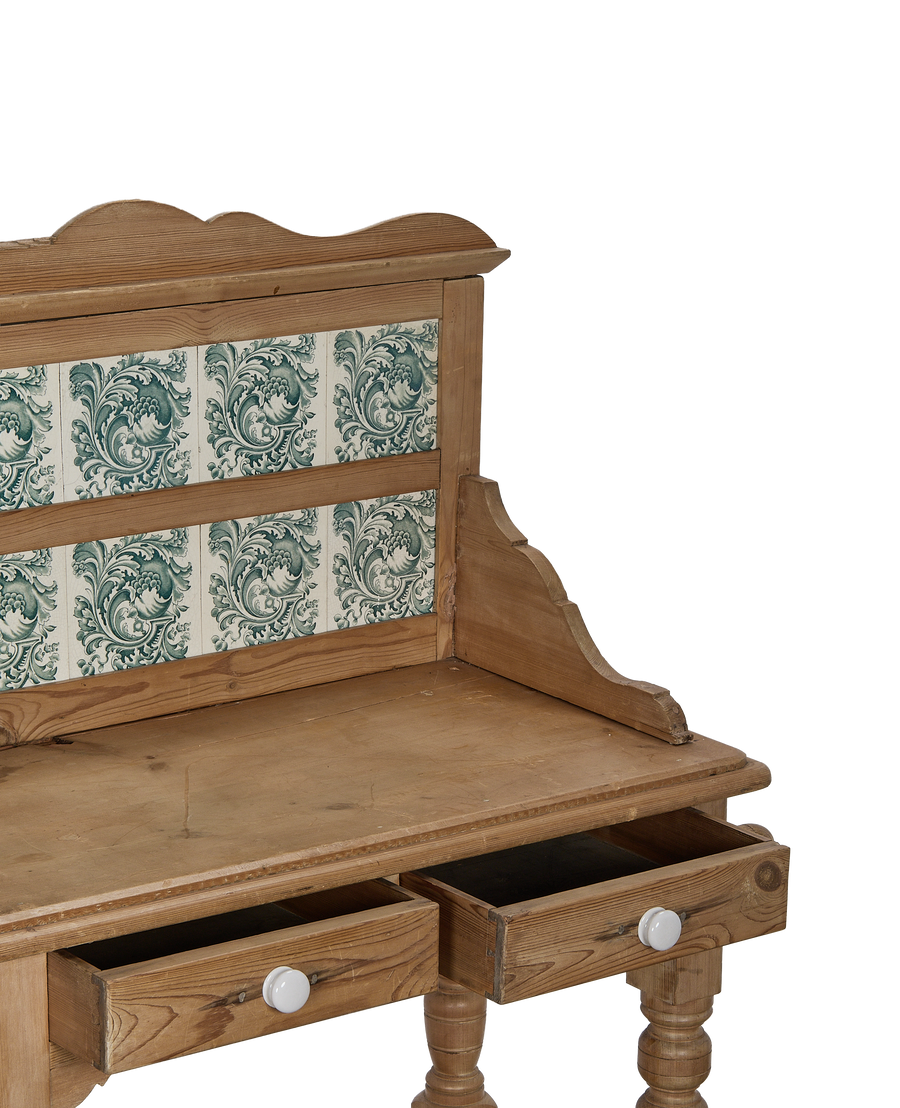 Vintage oak kitchen display cabinet with opening drawers and ornate green tiles.