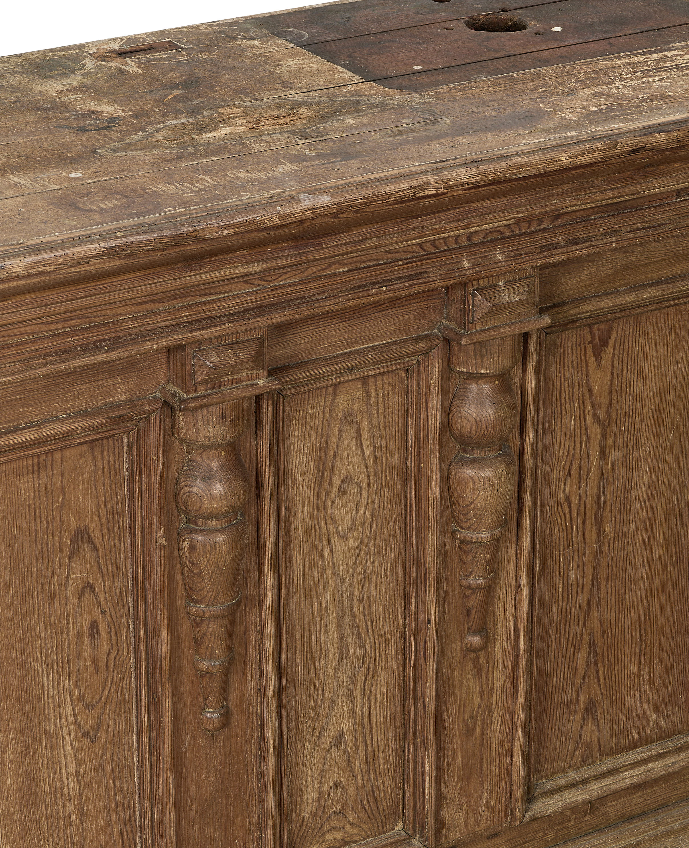 Vintage French oak shop counter with detailed decorative carved pilasters and aged wood grain.