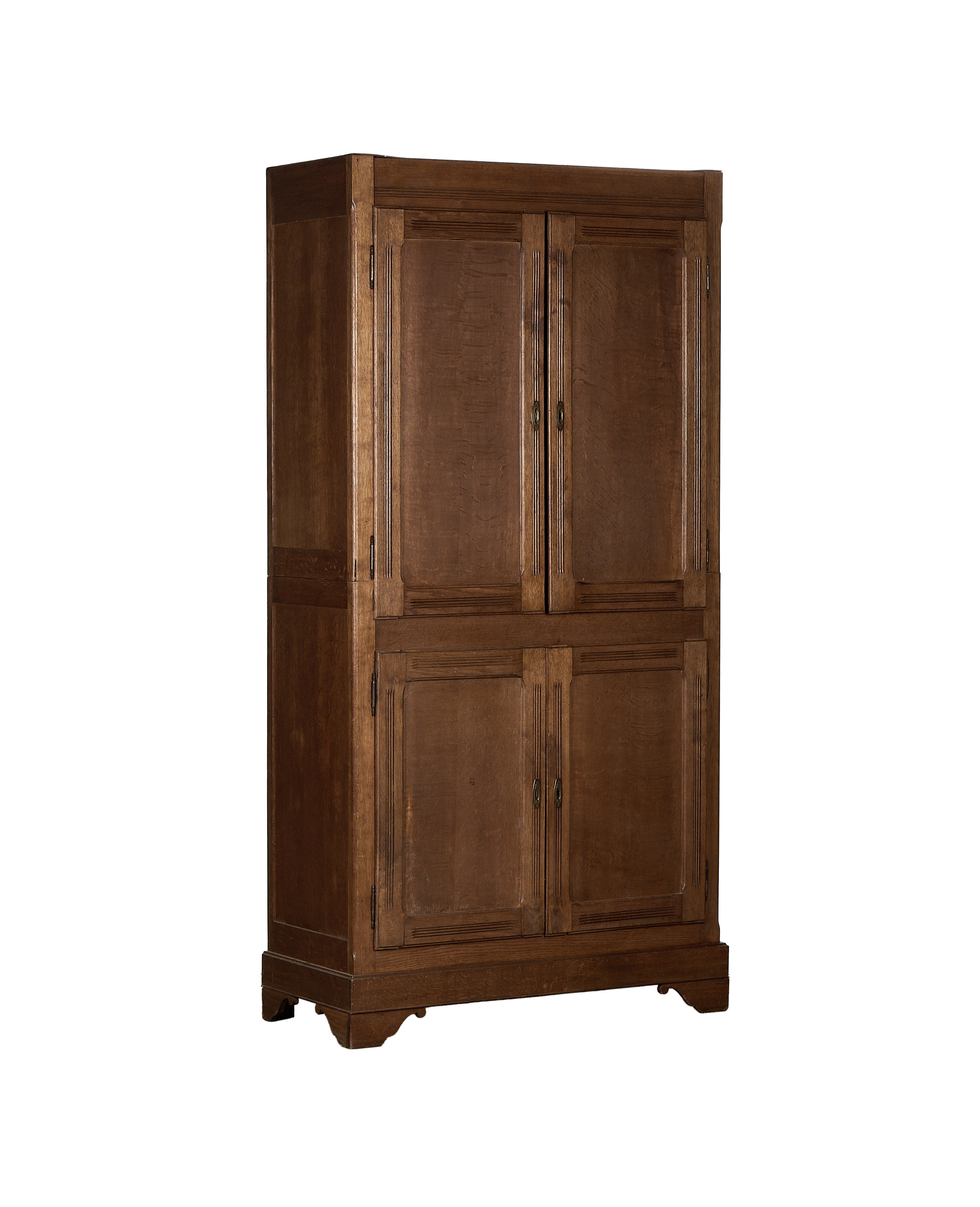Full frontal view of the vintage French oak armoire with paneling and brass hardware.