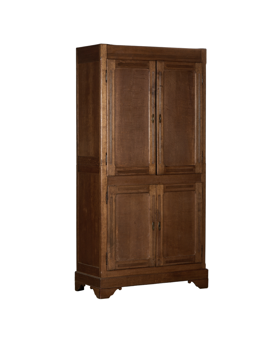 Full frontal view of the vintage French oak armoire with paneling and brass hardware.
