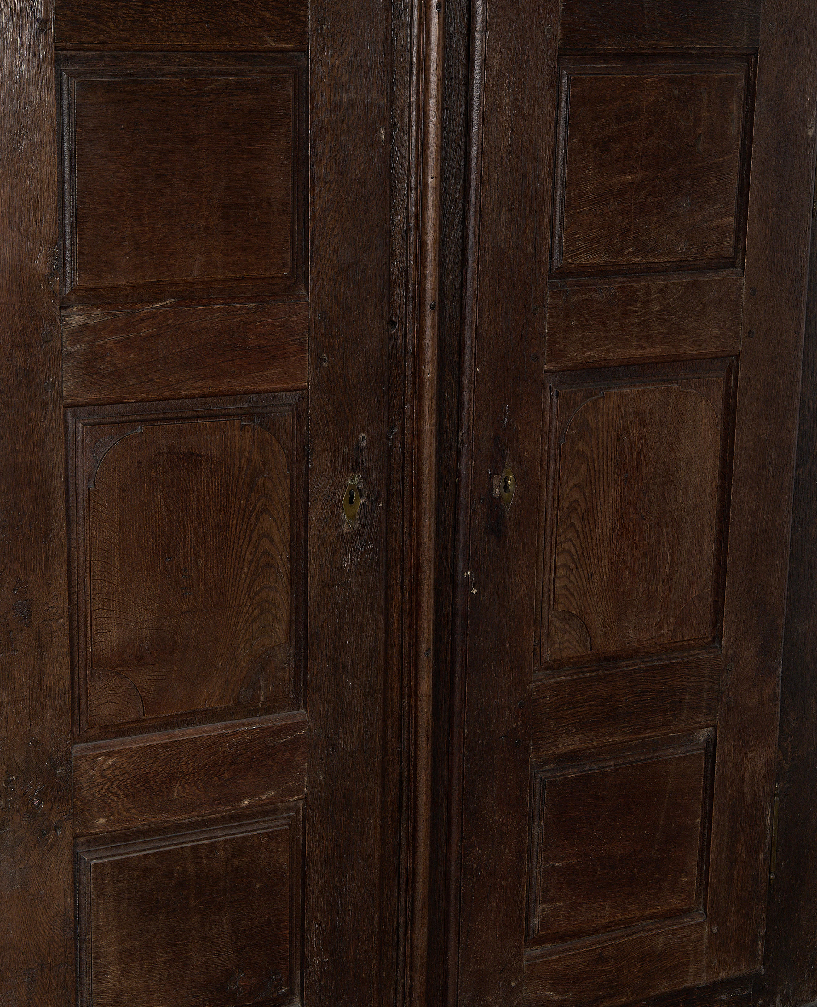 Paneled doors of vintage 1850s French oak cabinet, showing natural wear and keyholes.