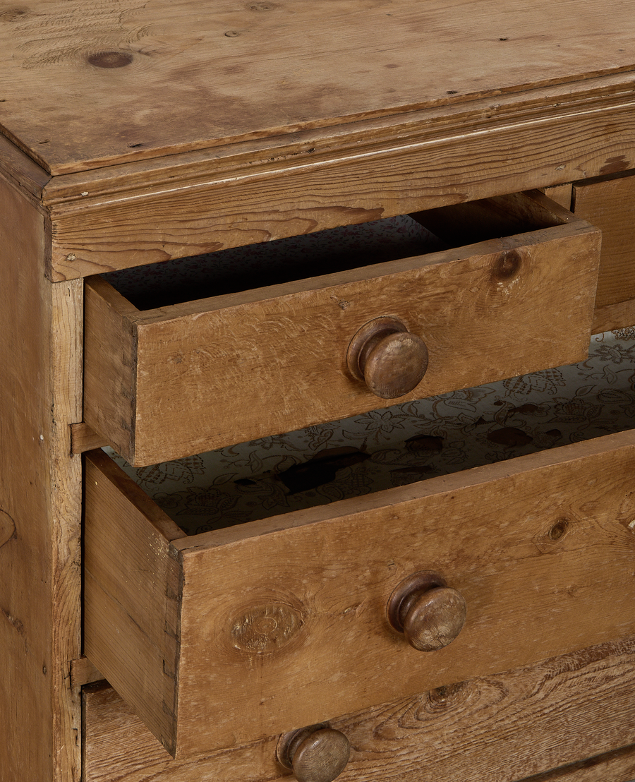 Vintage French pine chest of drawers with two top drawers partially open, revealing patterned lining.