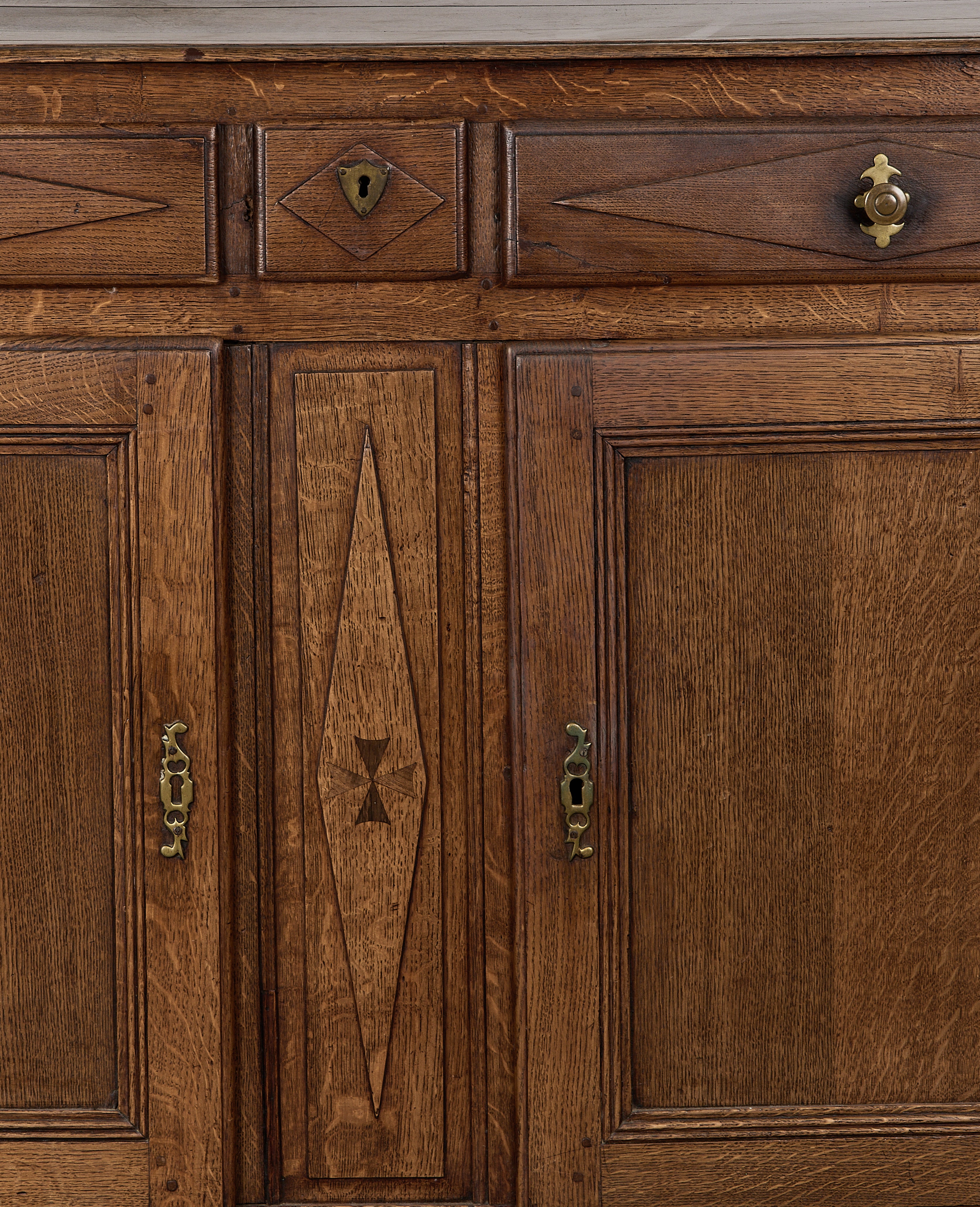 Vintage French oak dresser close-up, showing intricate carving, brass hardware, and unique wood grain.