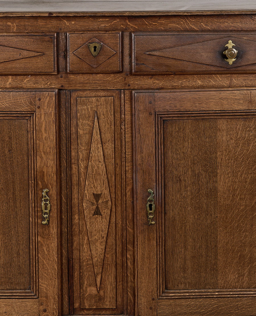 Vintage French oak dresser close-up, showing intricate carving, brass hardware, and unique wood grain.