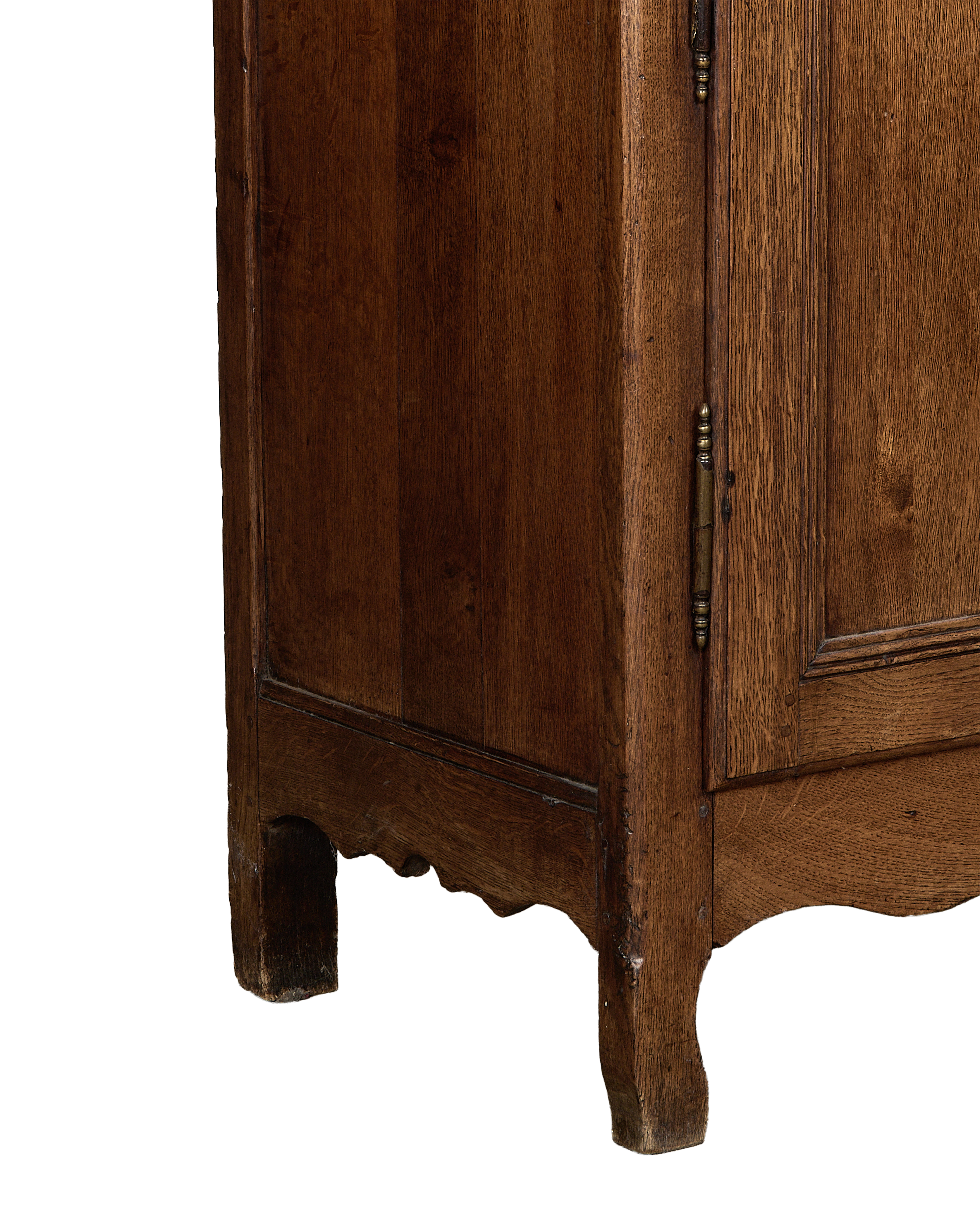 Vintage French oak dresser corner, showing worn brass hinge, scalloped base, and distressed wood.