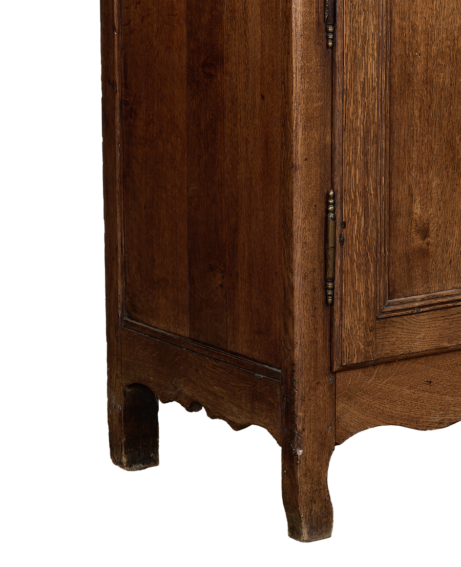 Vintage French oak dresser corner, showing worn brass hinge, scalloped base, and distressed wood.