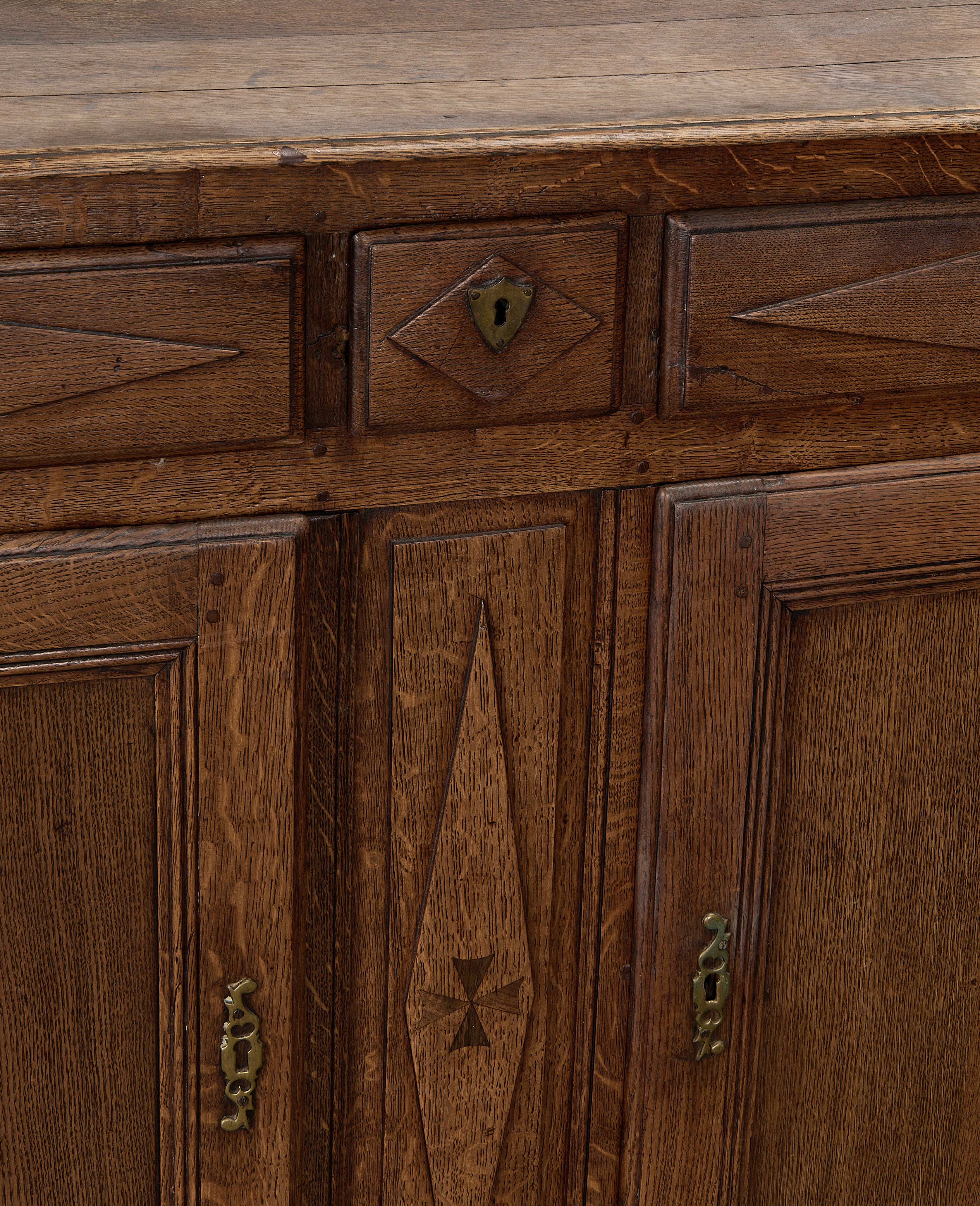 Vintage French oak dresser close-up showing keyholes, inlaid motif, and distressed patina.