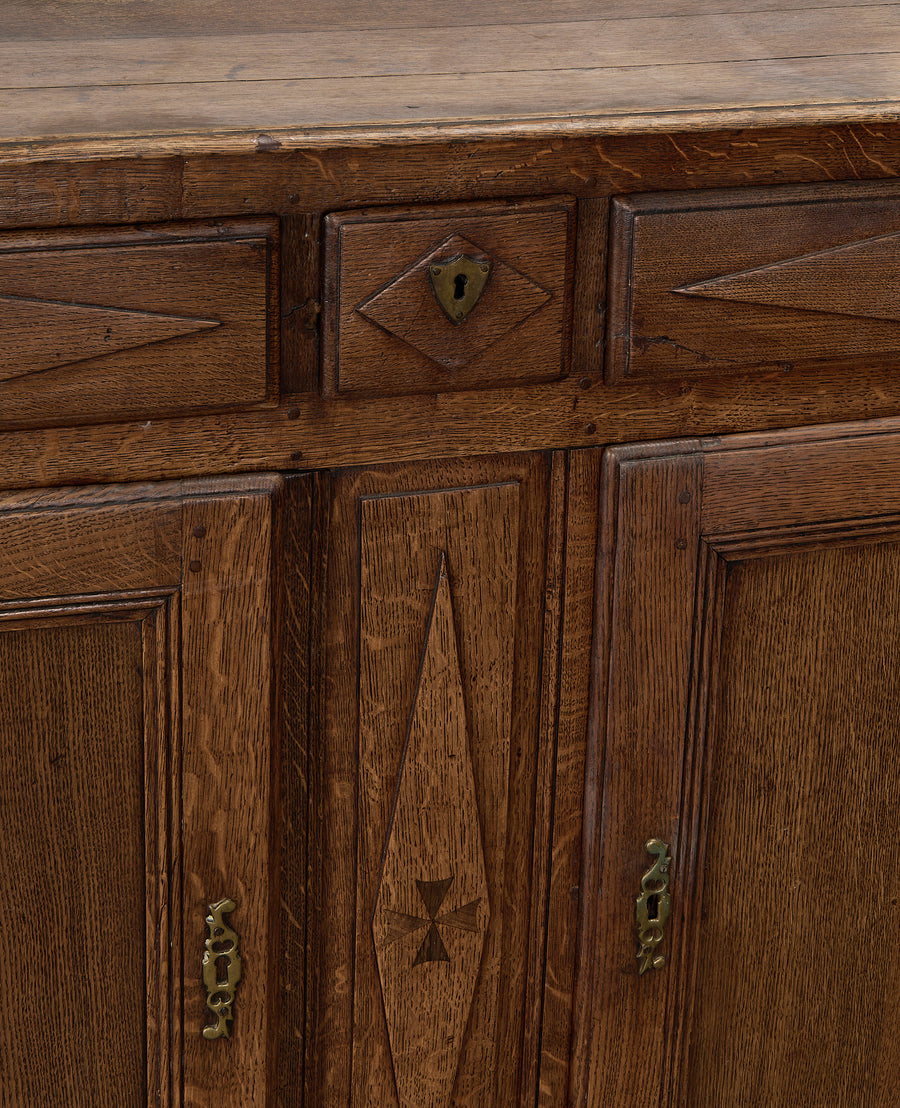 Vintage French oak dresser close-up showing keyholes, inlaid motif, and distressed patina.