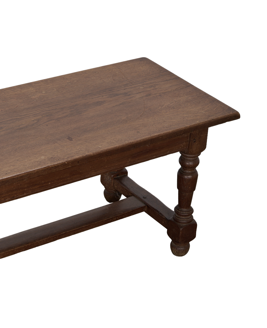 Vintage French oak coffee table with ornate turned legs and stretcher, showing aged details.