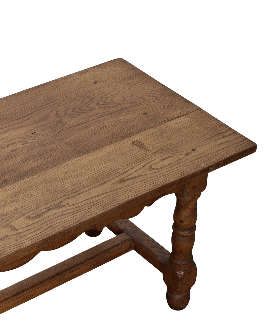 Vintage French oak coffee table showcasing its rustic top surface and carved leg detail.