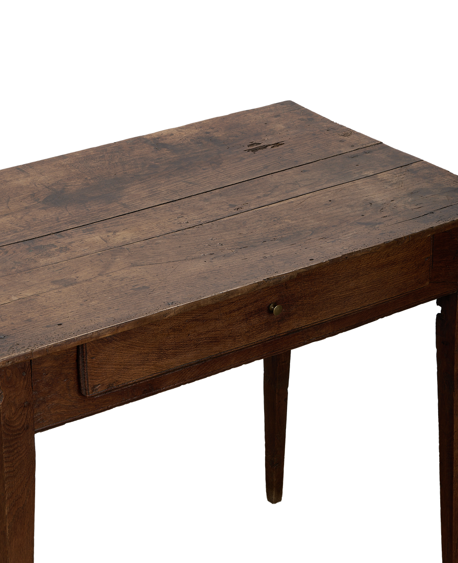 Vintage French oak wooden desk, showing distressed tabletop, single drawer, and tapered leg.