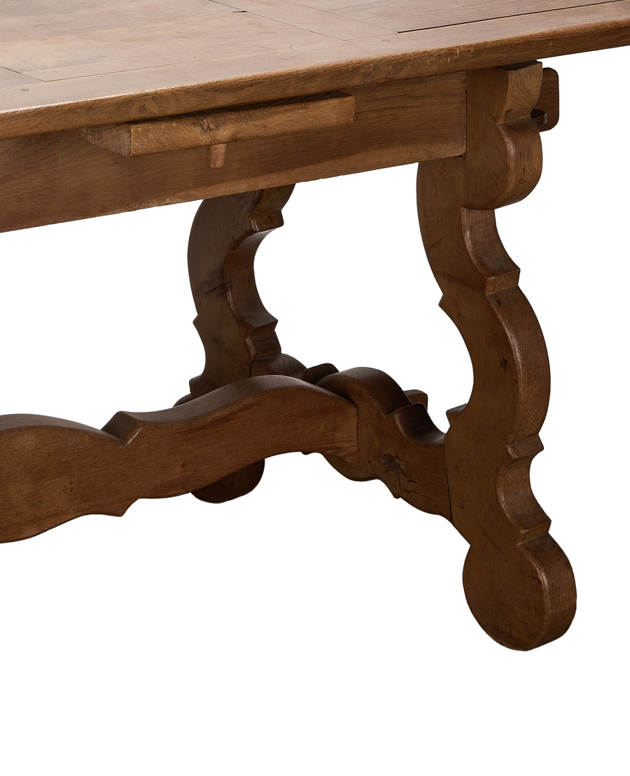 Vintage French oak refectory table, showing extendable leaf supports and scrolled trestle base.