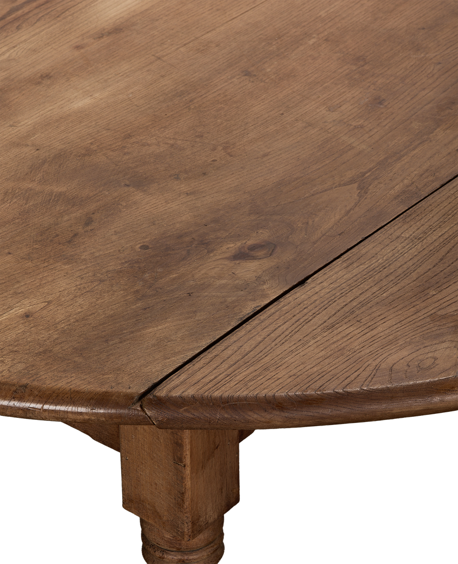 Close-up of vintage French oak drop leaf table's aged wood grain and joinery.
