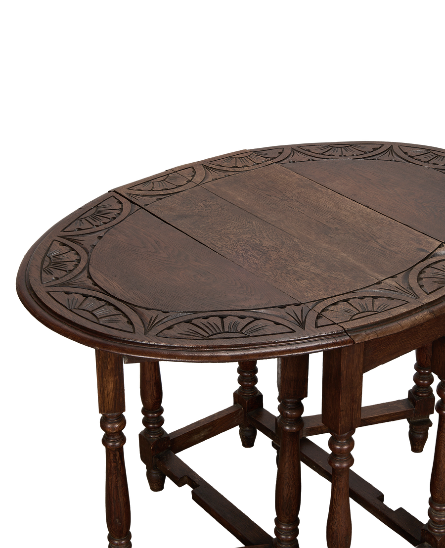 Vintage French oak gate leg table, close-up showing carved sunburst edge detail.