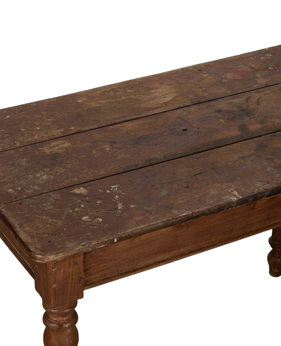 Vintage French oak farm table surface, showcasing distressed reddish-brown wood planks with paint splatters.