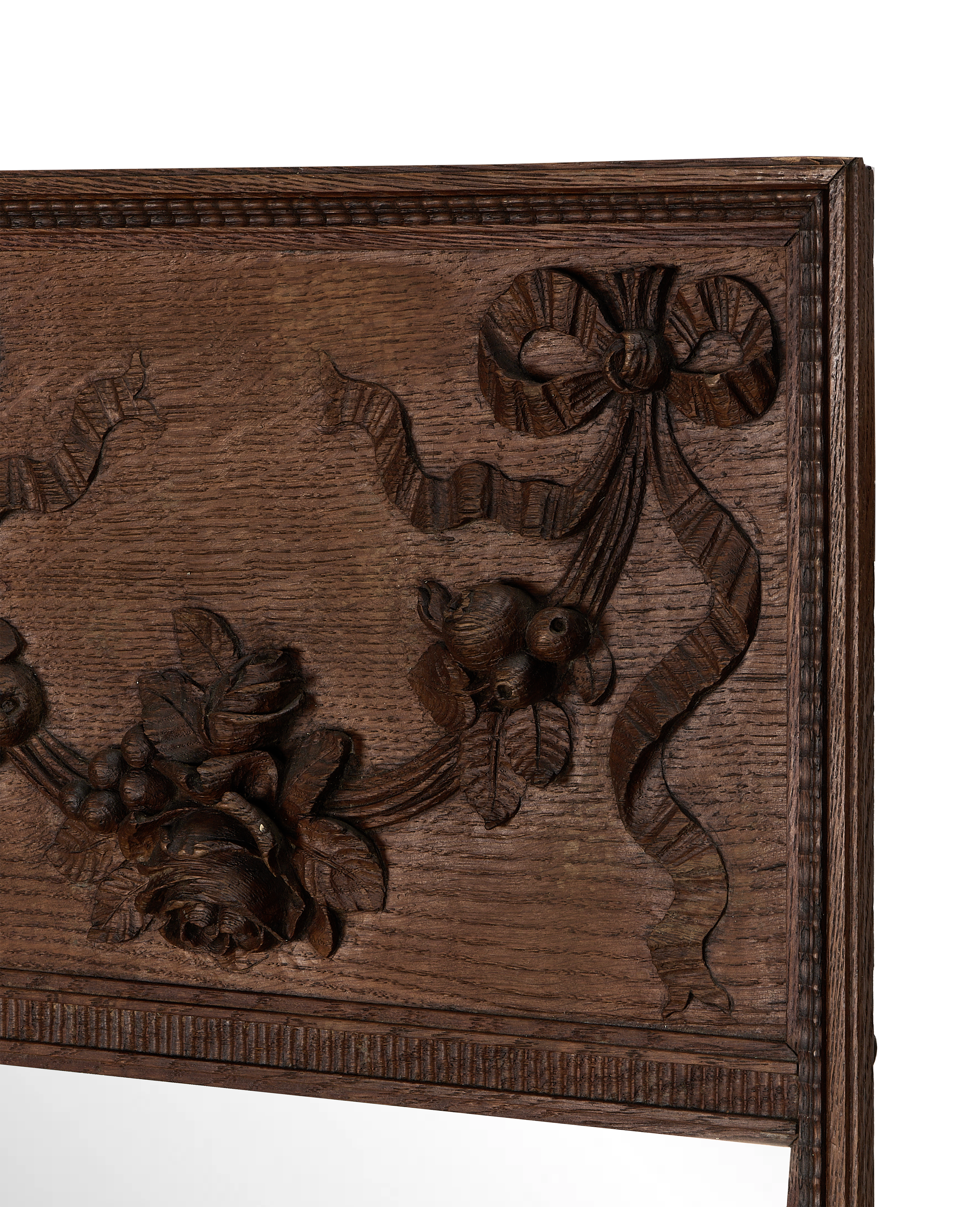 Close-up of vintage French oak mirror frame, showing intricate floral, ribbon carvings.