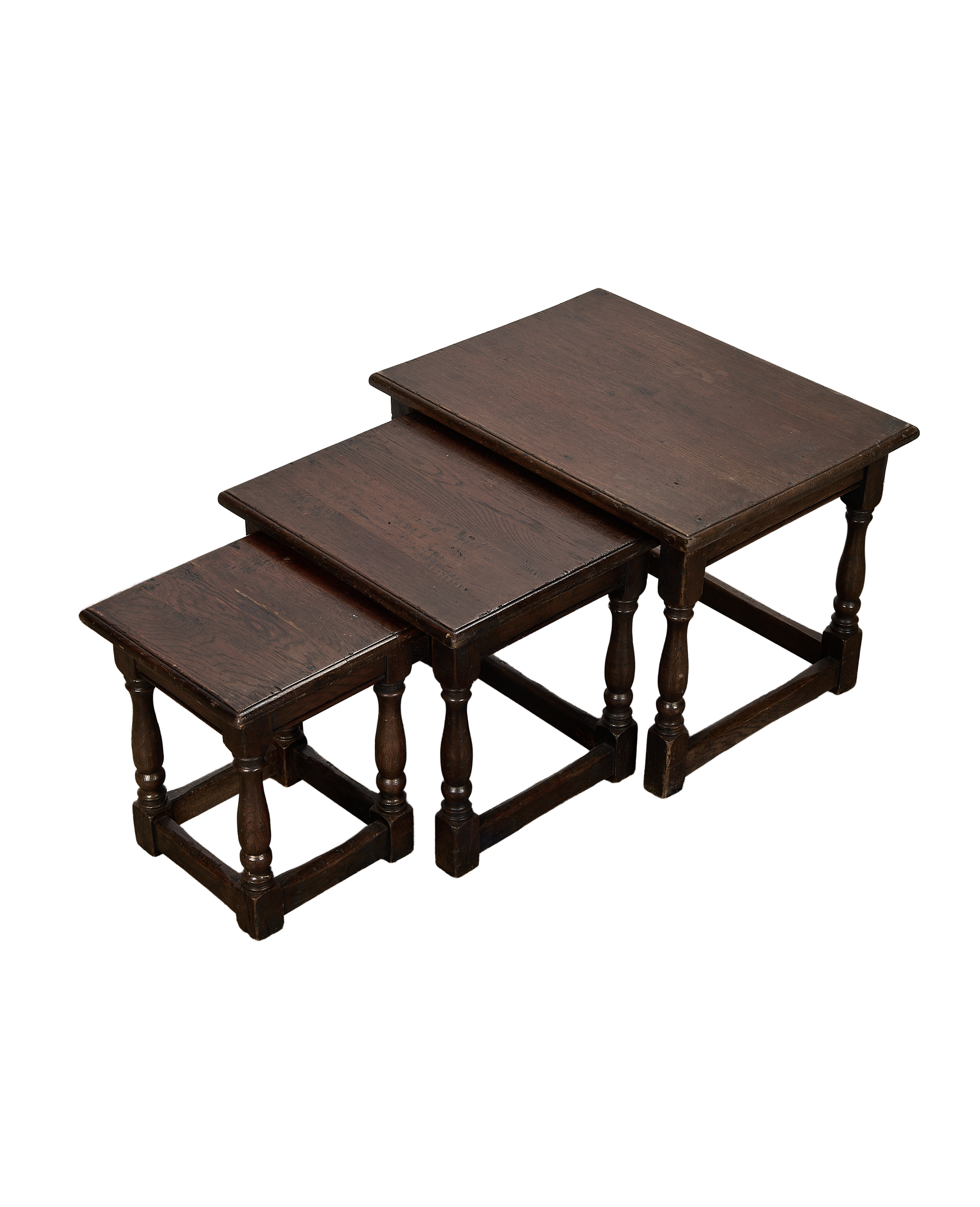 Top-down angle of three vintage French oak nesting tables with turned legs.