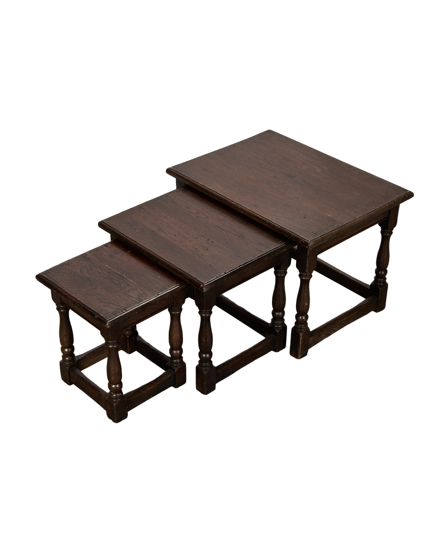Top-down angle of three vintage French oak nesting tables with turned legs.