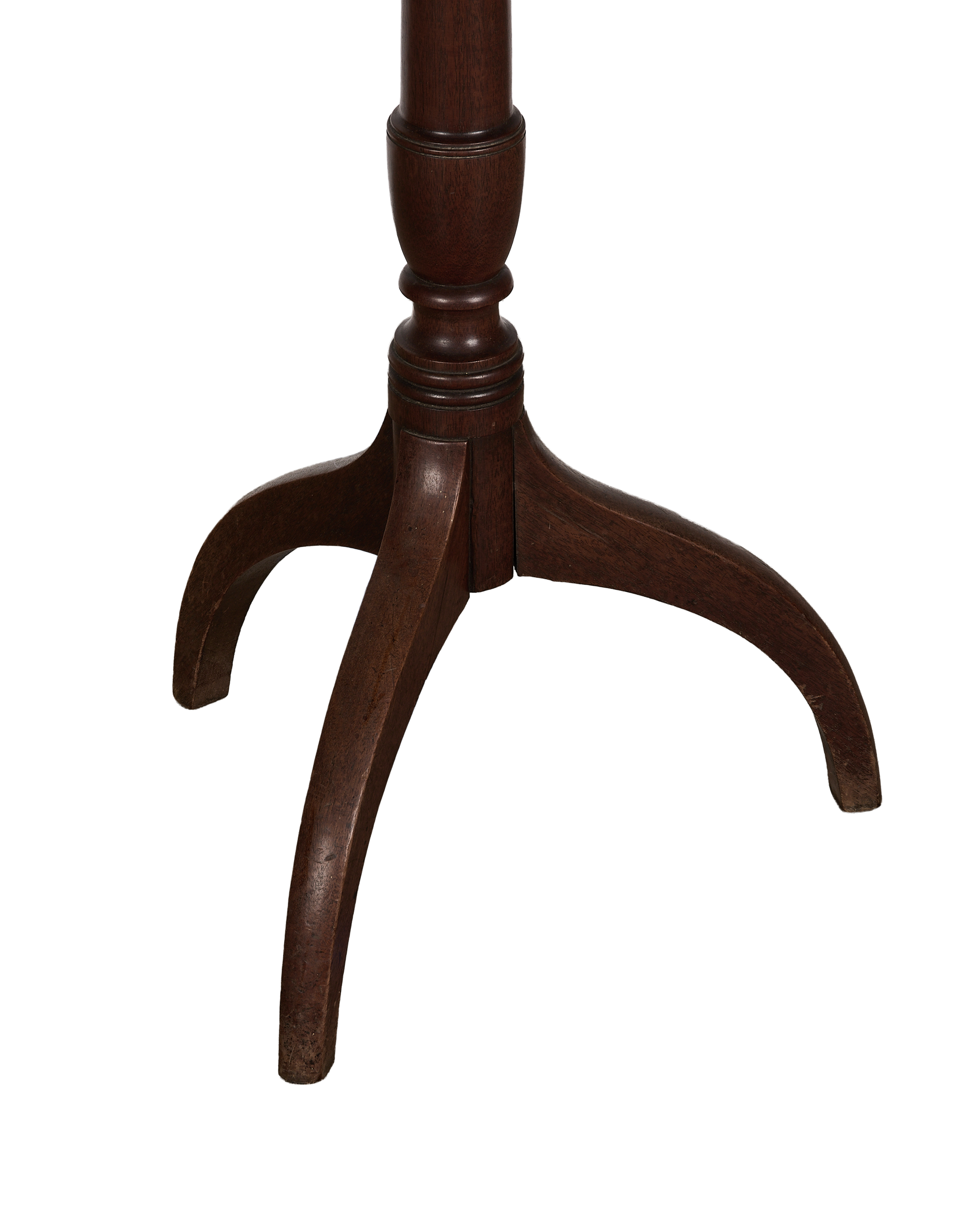 Close-up of vintage French oak bistro table's dark wood tripod base and scrolled feet.