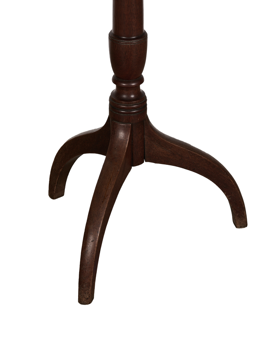 Close-up of vintage French oak bistro table's dark wood tripod base and scrolled feet.