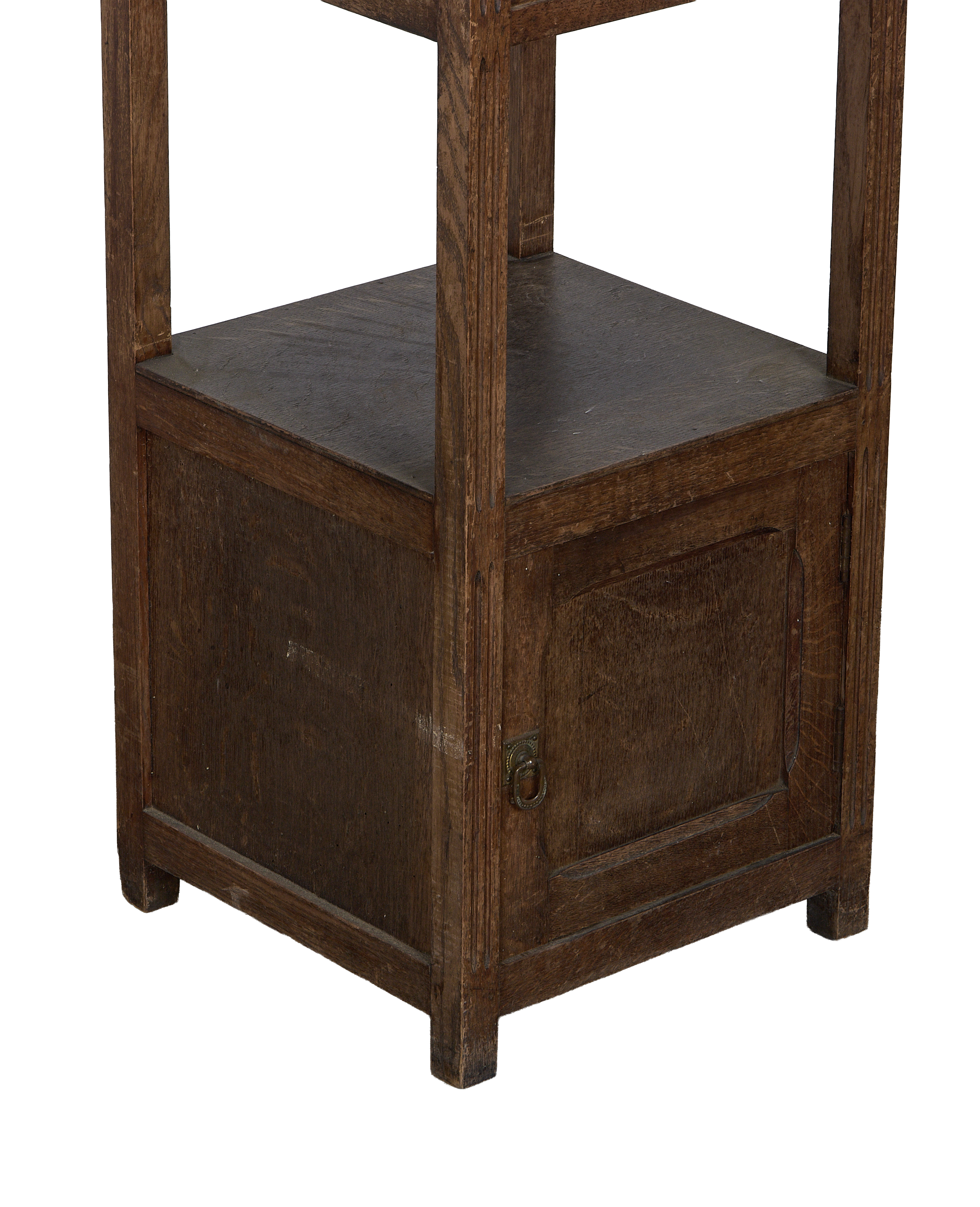 Vintage oak nightstand's bottom section, showing one cabinet door with aged brass ring pull.