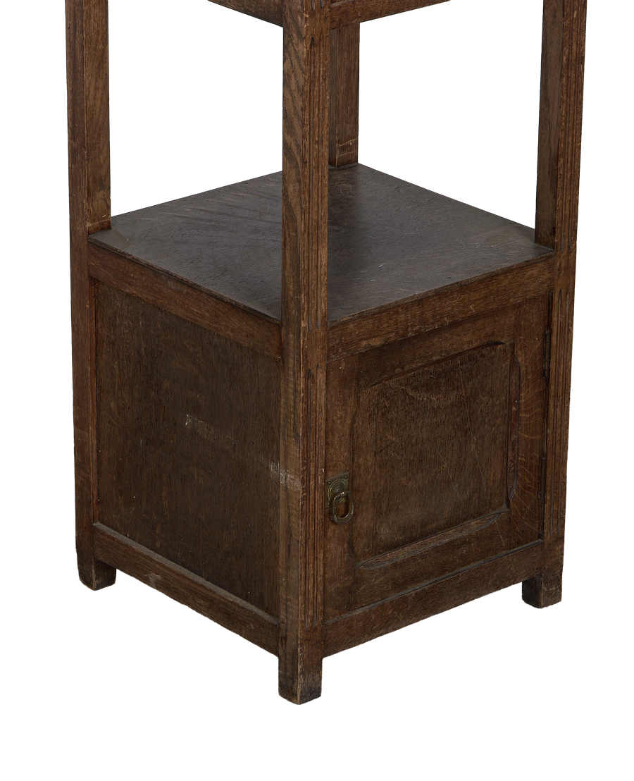 Vintage oak nightstand's bottom section, showing one cabinet door with aged brass ring pull.