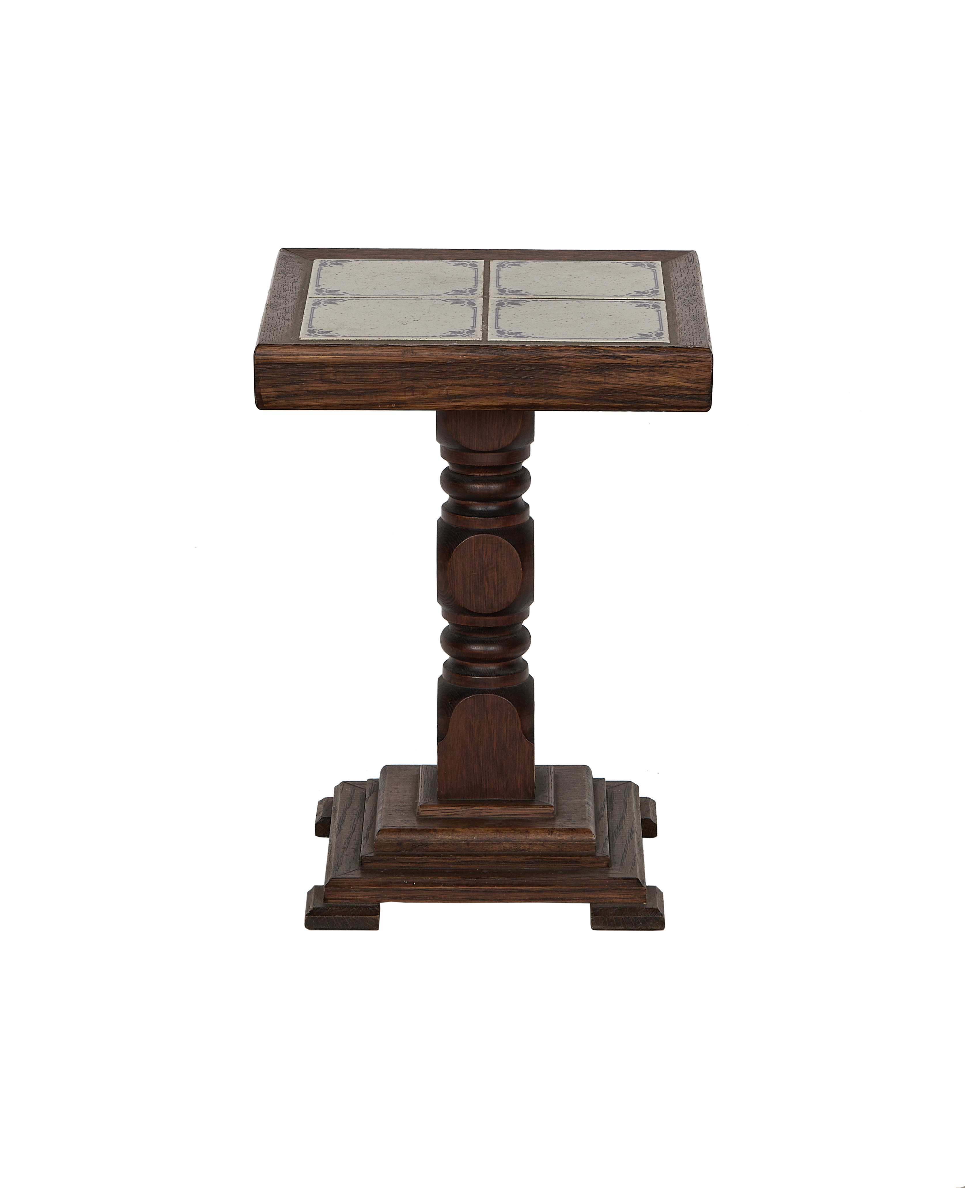 Close-up of vintage French oak side table with ornate Delft tile top.